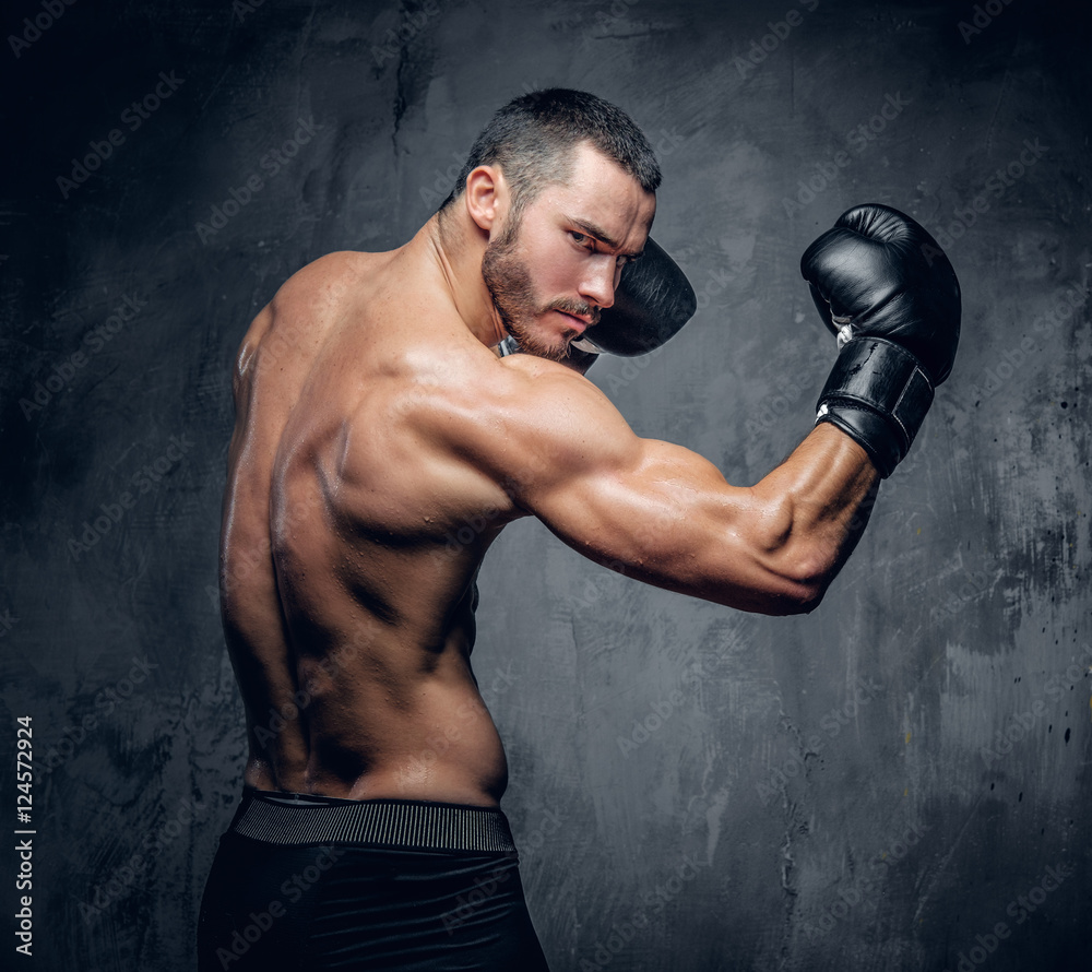 Aggressive shirtless boxer on grey background.