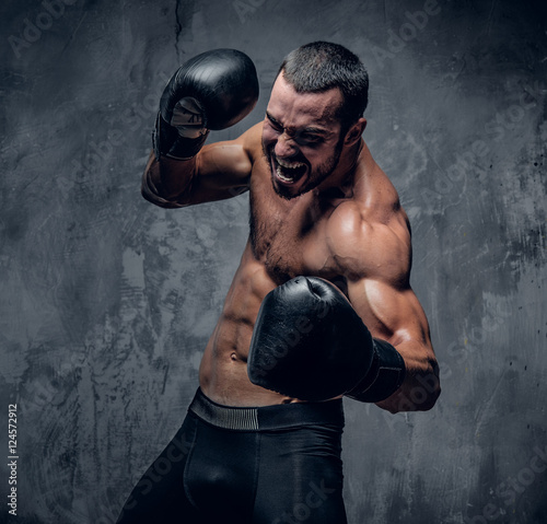 Aggressive shirtless boxer on grey background. photo