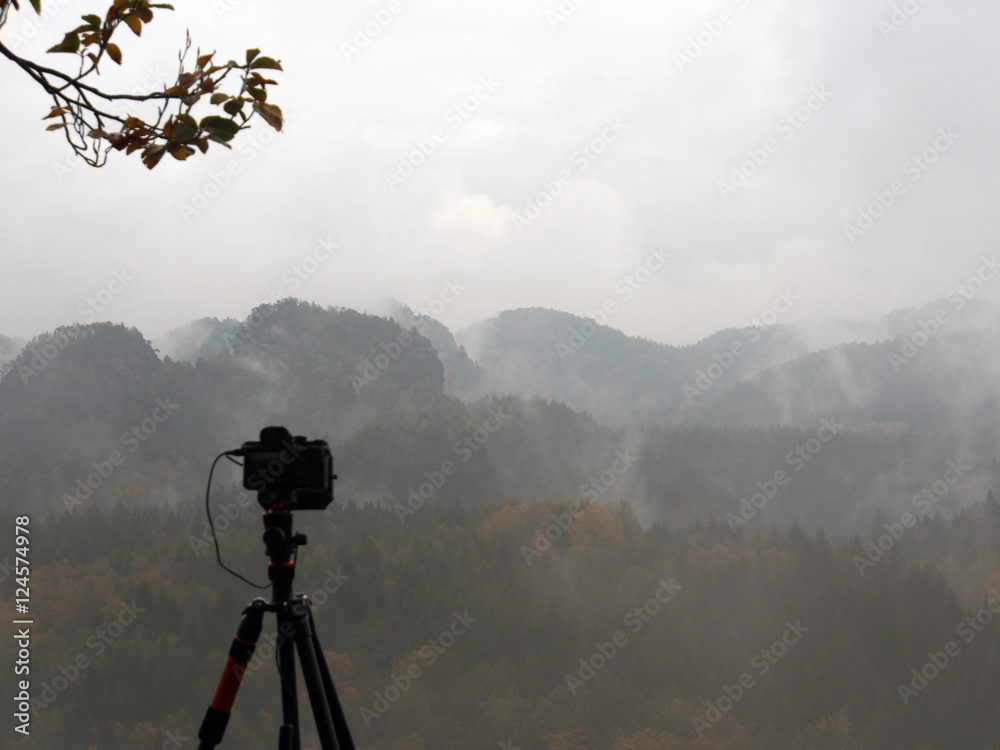Kamera und Stativ vor bewölkter Landschaft Kamera und Stativ vor bewölkter Landschaft