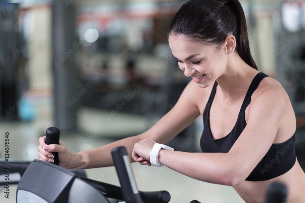 Active woman looking at smart watch in a gym Active woman looking at smart watch in a gym