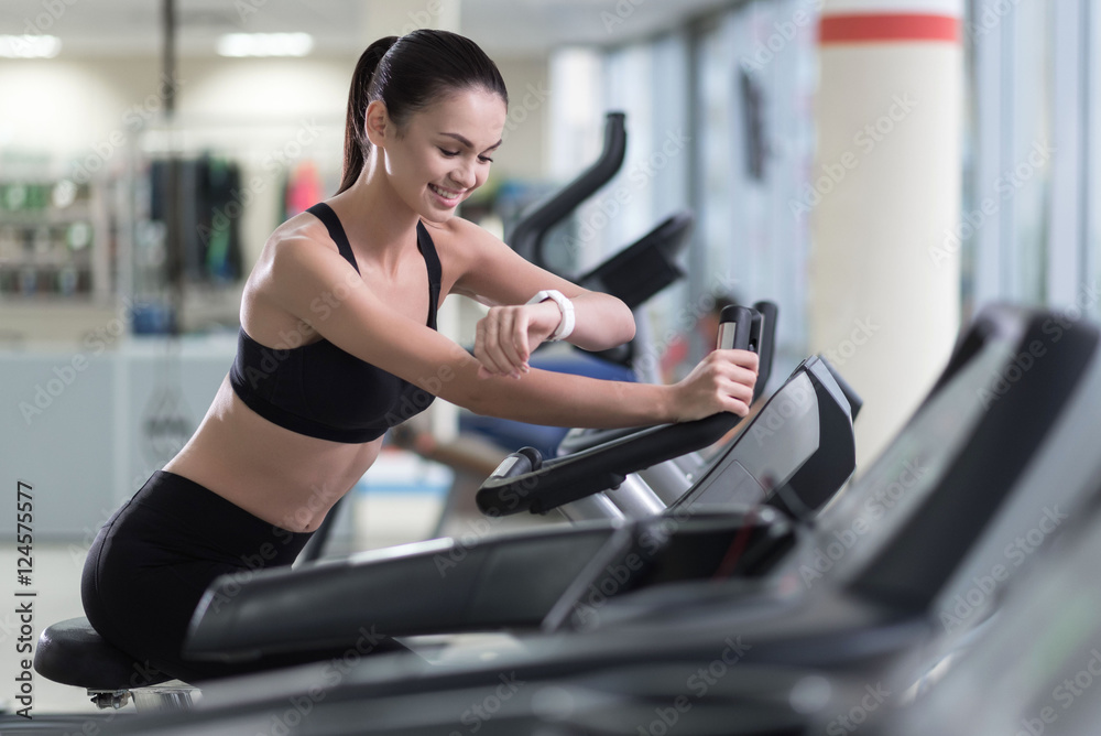 Active girl running on a treadmill and wearing smart watch
