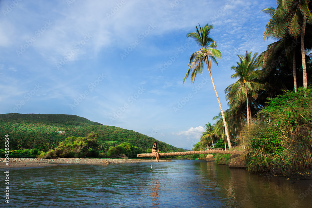 Obraz premium Holidays, woman sitting on a palmtree