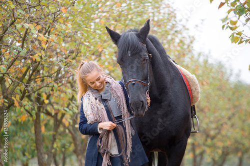 Beautiful stylish girl in a cowboy hat with a horse walking in the autumn forest, country style