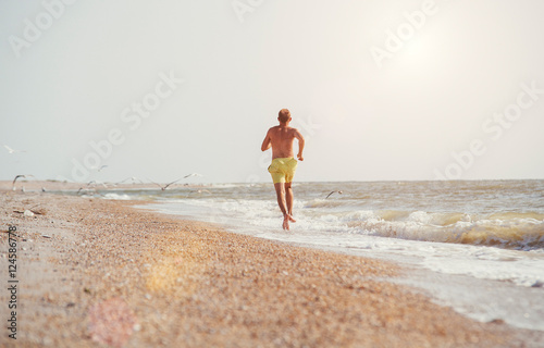 Man jogging on the desert sea line at the morning time © Soloviova Liudmyla