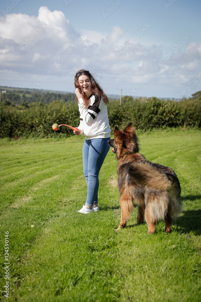 Φωτογραφία Vertical shot of teenage girl playing with her dog outside in a field