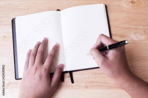 Writing in blank book on wooden table