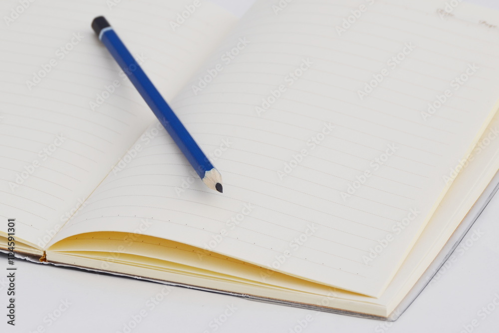 Naklejka premium Blue pencil on blank notebook.