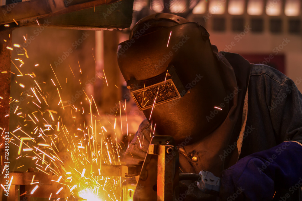 Worker is welding steel part in  factory