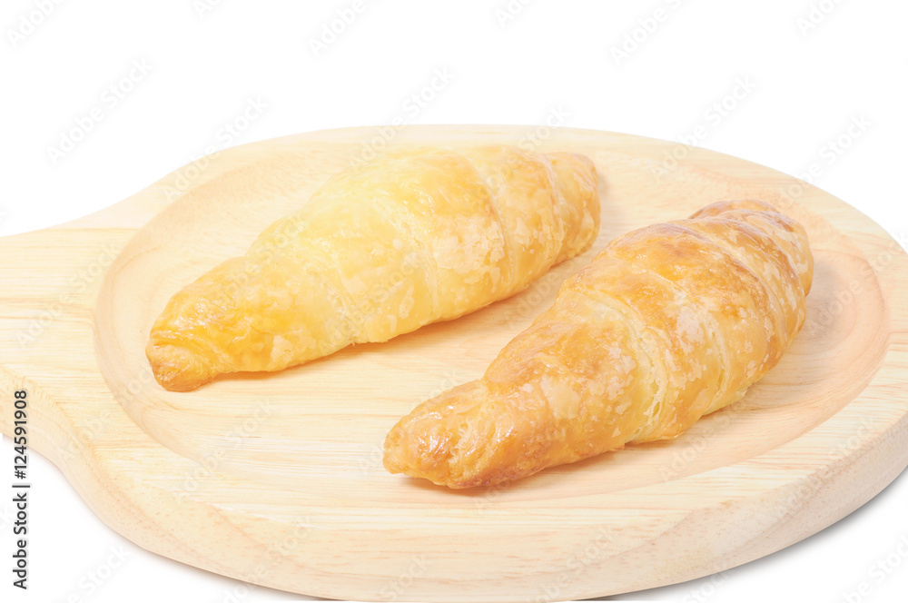 Double croissants on wooden plate with light flare