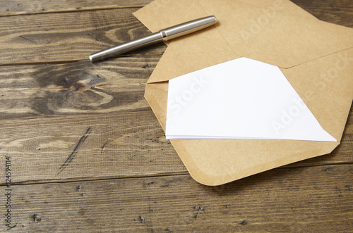 An open brown envelope with letter and writing pen on a rustic wooden background