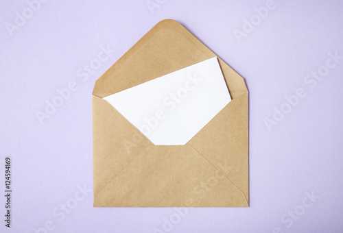 An open brown envelope with letter on a pastel purple background
