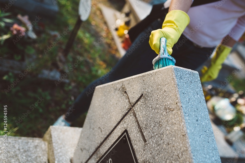 Woman cleans a grave with brush