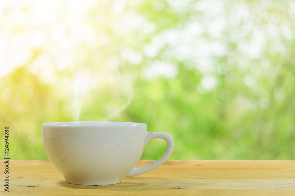 Close up of the white coffee mug on a wooden floor with a beautiful green nature background. Close up of the white coffee mug on a wooden floor with a beautiful green nature background.