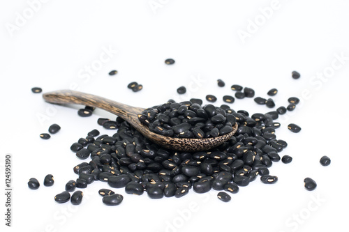 Black beans with wooden spoon on white background..
