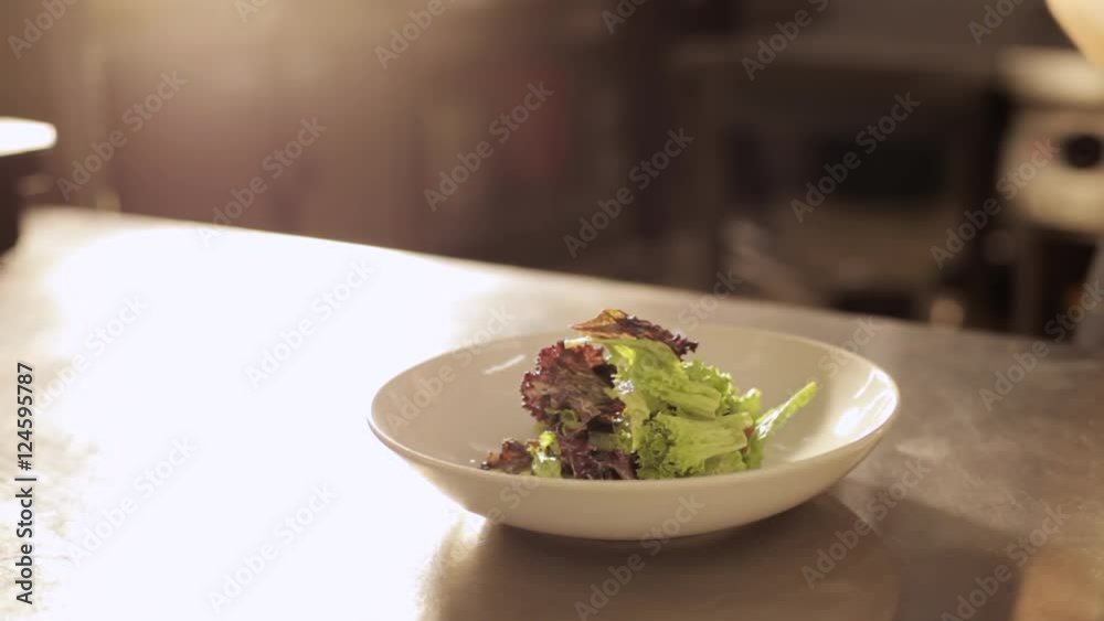 Hands of chef in gloves puts a salad from bowl on a plate. Hands of chef in gloves puts a salad from bowl on a plate.