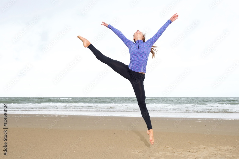 Dancer leaping in air into split on beach Dancer leaping in air into split on beach