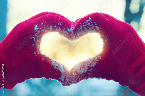 Heart from hands on winter background