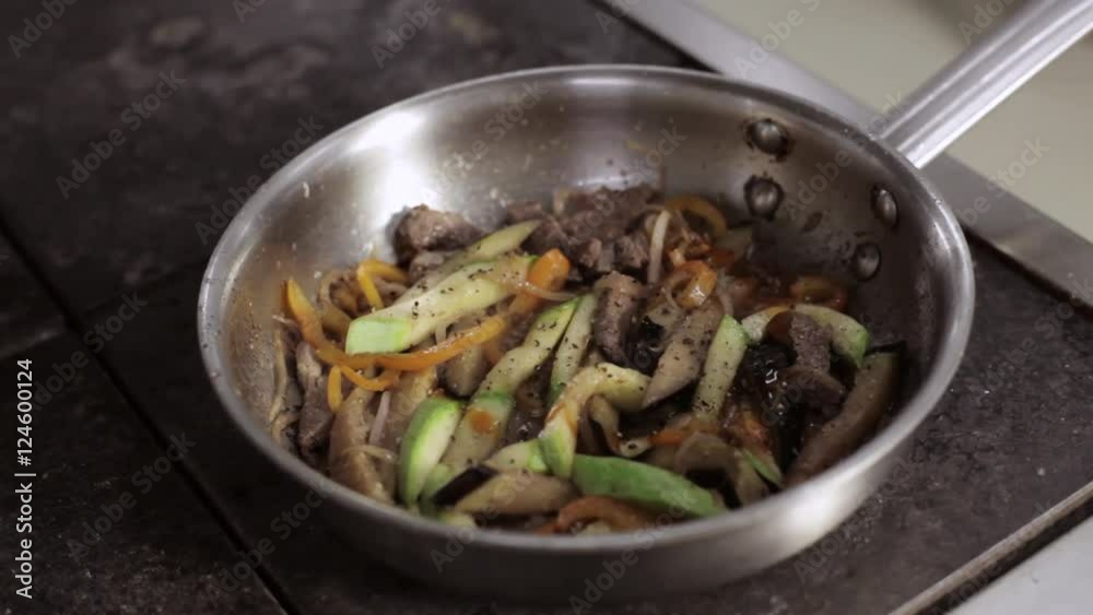 Chef adding tomato sause to frying pan with vegetables and meat. Chef adding tomato sause to frying pan with vegetables and meat.