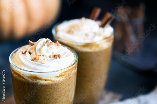 Two glass cups of pumpkin latte topped with whipped cream walnut