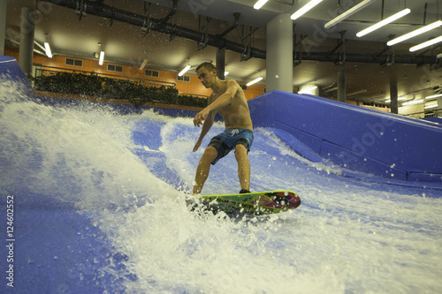 man surfing and enjoy on flowrider in aquapark photo