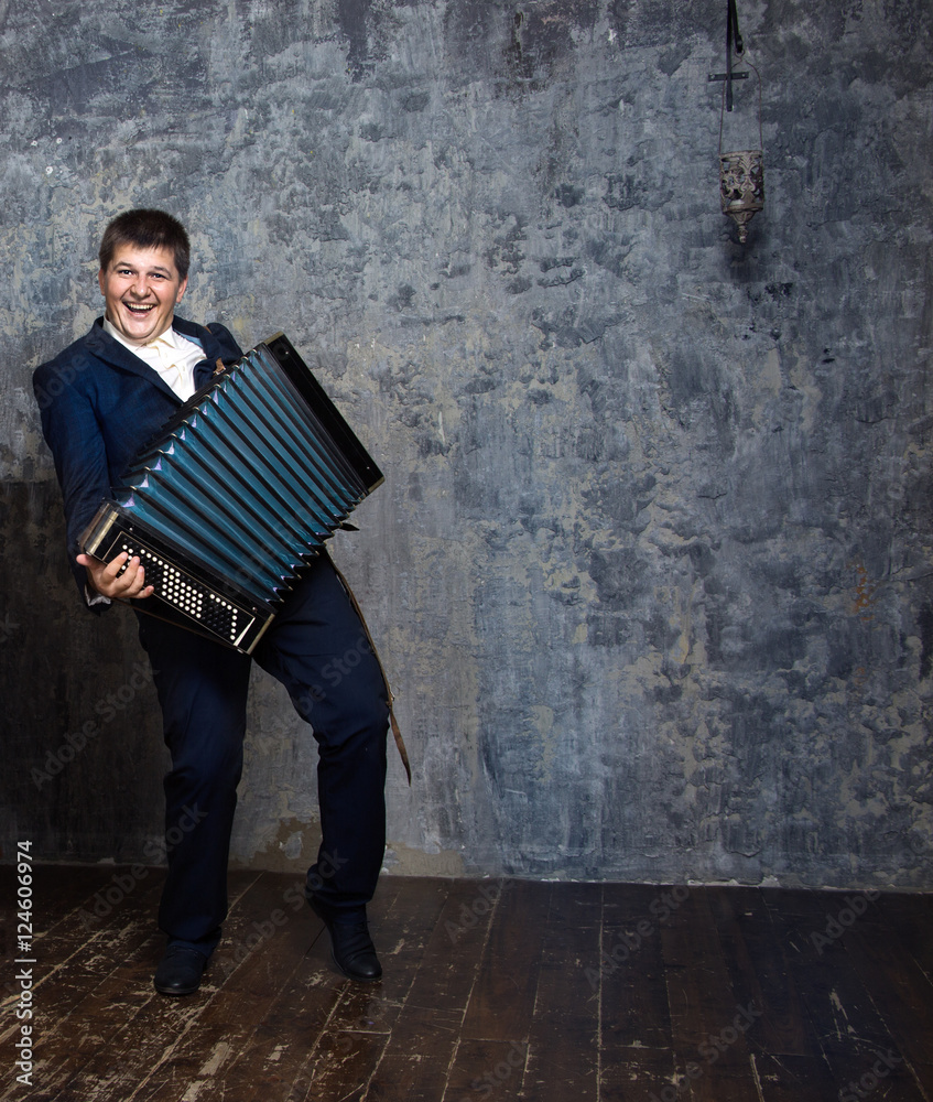 Brunette man in a blue suit playing the accordion