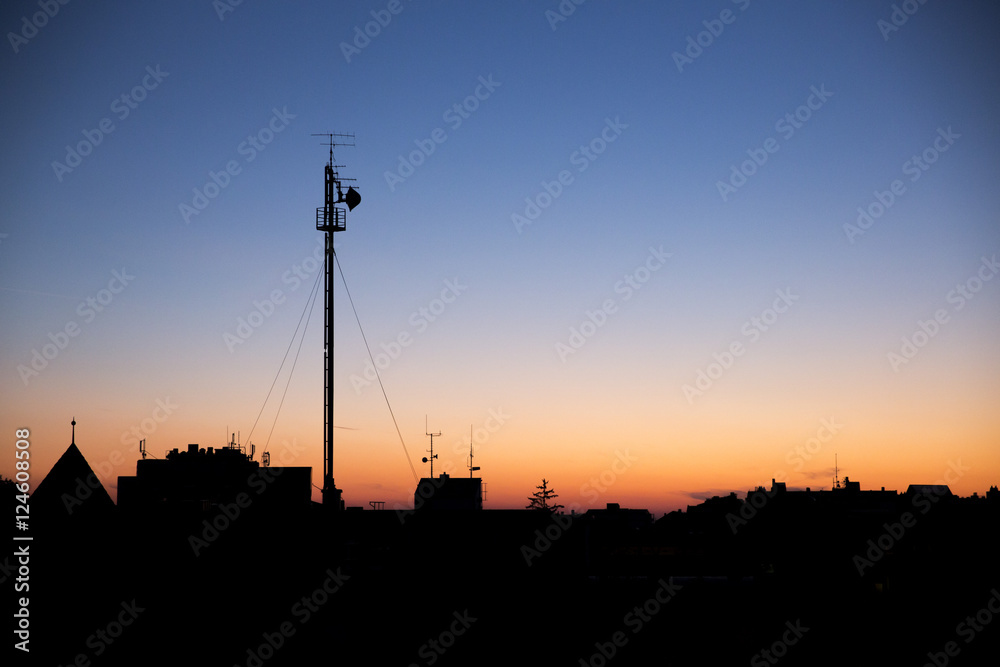 Silhouette cityscape with big radio tower under blue and orange Silhouette cityscape with big radio tower under blue and orange