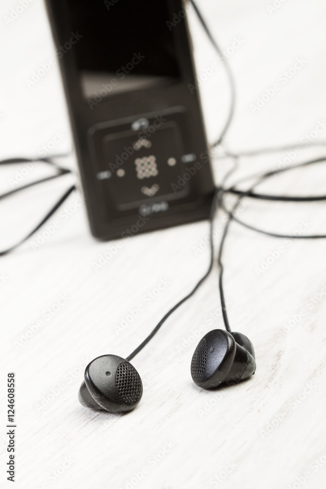 Aparato de música mp3 con cascos auriculares sobre un fondo blanco rústico.  Vista de frente y de cerca Stock Photo | Adobe Stock