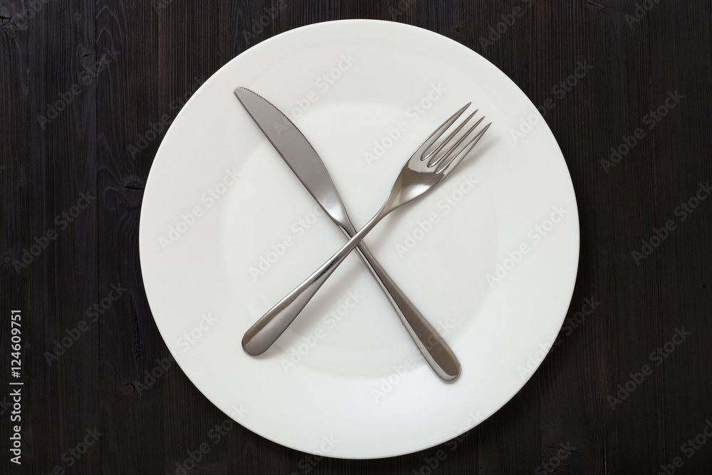 top view of white plate with cultery on dark brown top view of white plate with cultery on dark brown
