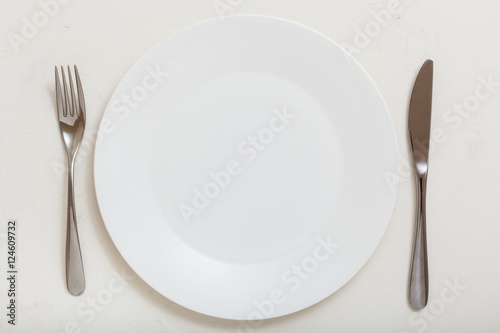 top view of white plate with knife, spoon on white