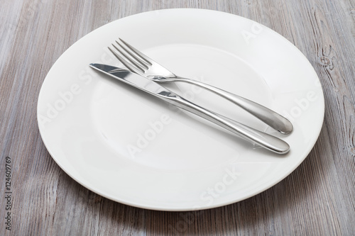 white plate with parallel knife, spoon on gray