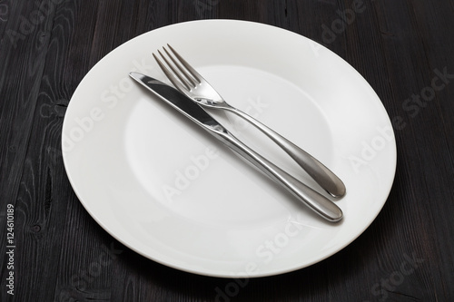 white plate with parallel knife, spoon on dark
