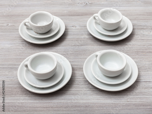 four white cups and saucers on gray brown table