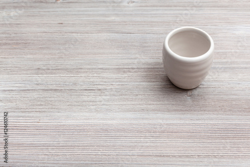 white cup for sake on gray brown wooden board