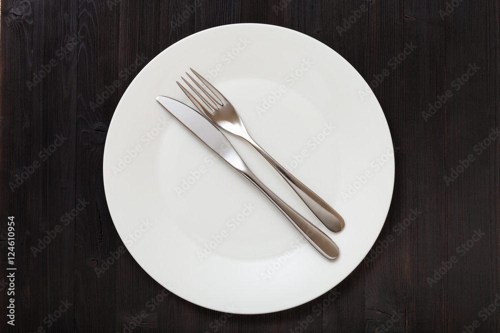 top view of white plate with flatware on dark top view of white plate with flatware on dark