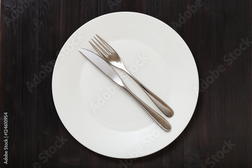 top view of white plate with flatware on dark