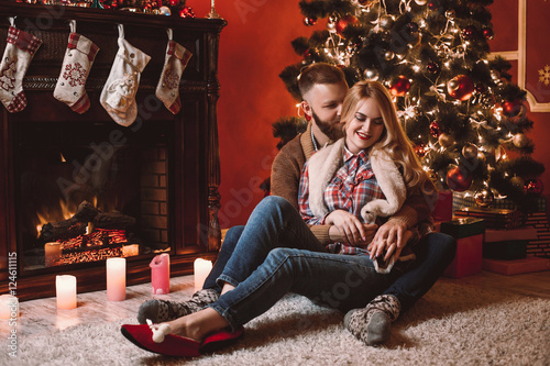 A couple of lovers resting by the fireplace in the Christmas room. Feet in woolen socks warming in winter time. © mikhail_kayl