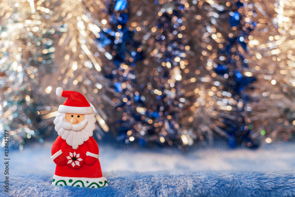 Figurine toy Santa Claus on Christmas colorful bokeh background.