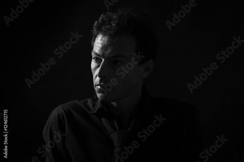 Man low key high-contrast profile portrait in backlight with a serious look on his face
