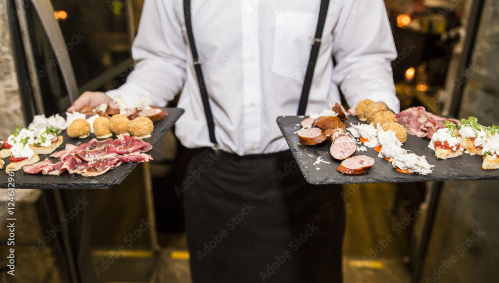 Waiter carry plates with cold starters from kitchen