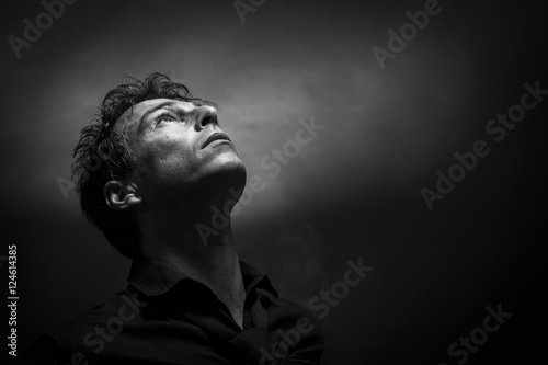 Isolated thinking man face looking up. Low key , black and white portrait. Hope concept