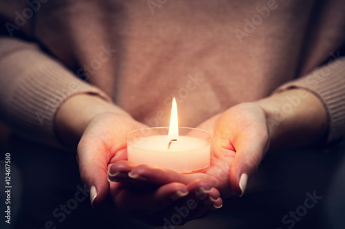 Candle light glowing in woman's hands. Praying, faith, religion