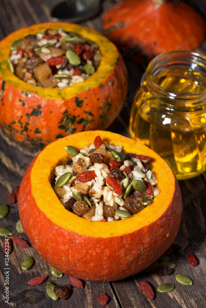 sweet rice with dried fruit and nuts in pumpkin on wooden table
