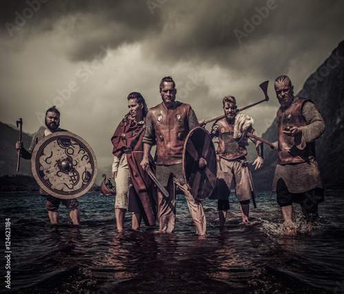 Photo A group of armed Vikings standing on river shore