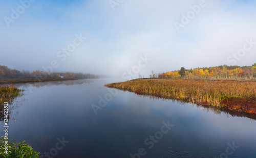 Morning mist and fog rises from warm water into autumn October air on Corry lake, Ontario, Canada.