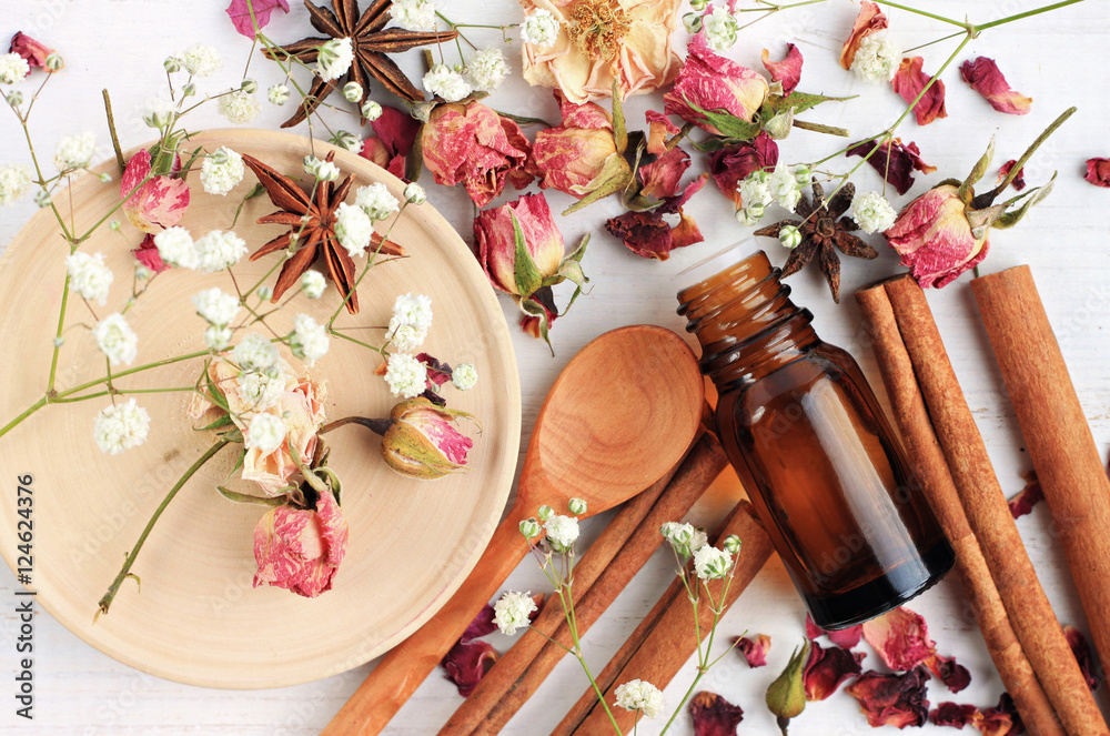 Essential oil of rose, cinnamon, anise mix. Herbal aroma beauty care. Dropper bottle, dried fragrant flowers, sticks, wooden utensils, top view background. - obrazy, fototapety, plakaty 