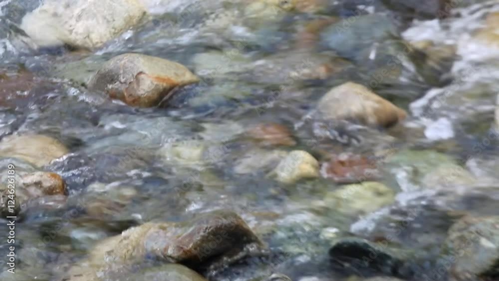 A rock bed in a shallow part of the rive. A river bed, clean and fresh, exposes the rocks scattered across the bottom. A rock bed in a shallow part of the rive. A river bed, clean and fresh, exposes the rocks scattered across the bottom.