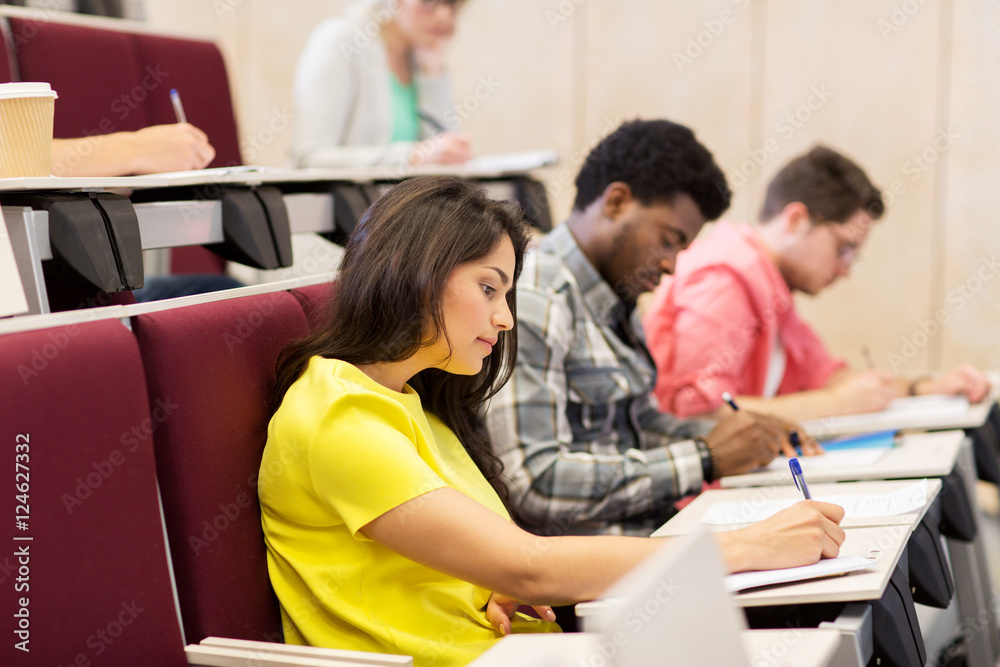 group of students with notebooks in lecture hall group of students with notebooks in lecture hall
