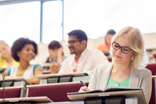 student girl writing to notebook in lecture hall