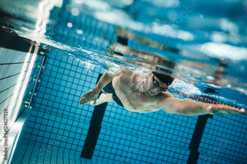 Young man swimming the front crawl in a pool.
