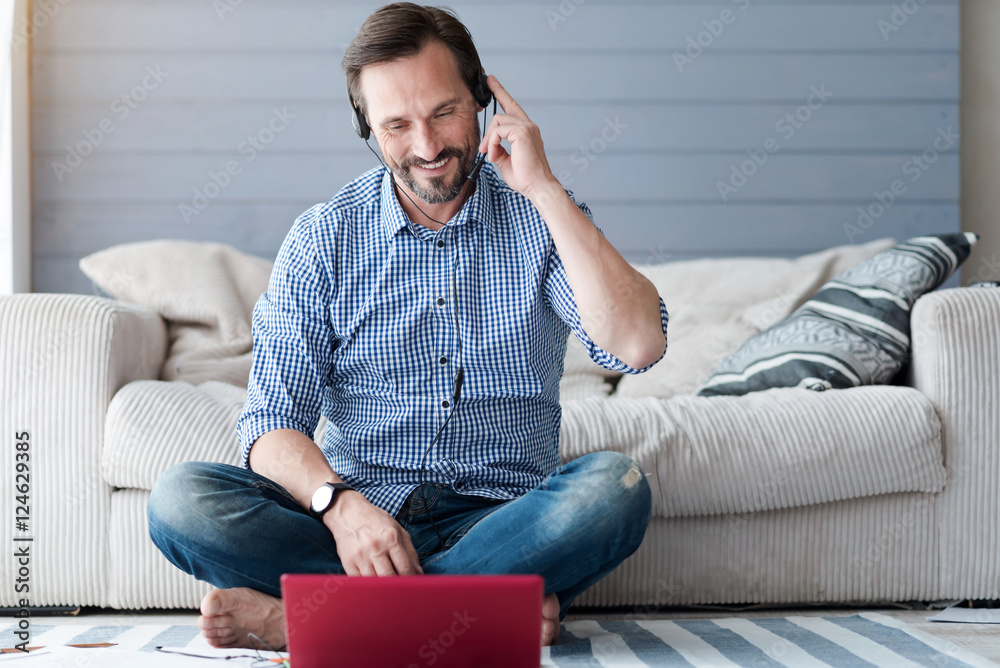 Bearded man sitting on floor with headphones using laptop Bearded man sitting on floor with headphones using laptop